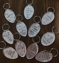 six hand stamped metal key chains with words on them, all in different styles and shapes