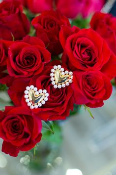 a vase filled with red roses and pearls