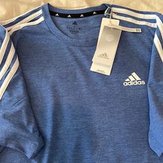 Brand New. Never Worn. Tags Attached. Adidas Multi Sport Tee Shirt. Short Sleeve. Size Medium. Regular Fit. Shoulder To Shoulder 17”. Armpit To Armpit 21”. Length 29”. Royal Blue Heather With 3 White Stripes. 65% Recycled Polyester. 35% Cotton. Blue Cotton Tops With Three Stripes, Adidas Blue Three Stripes Top, Adidas Blue Tops With Three Stripes, Blue Adidas Tops With Three Stripes, Adidas Blue Tops With Three Stripes Branding, Blue Adidas Tops With Three Stripes Branding, Blue Short Sleeve T-shirt With Three Stripes, Adidas Blue Sporty Shirt, Sporty Adidas Blue Shirt