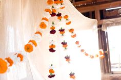 an orange and white flower garland hanging from a curtain in a room with sunlight coming through the window