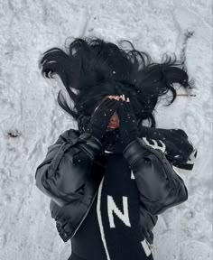 a woman with her hair blowing in the wind while wearing black gloves and holding her hands to her face