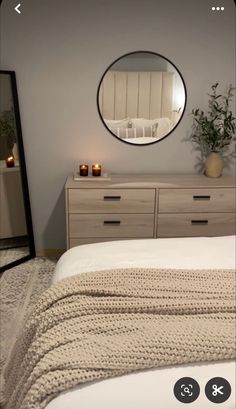 a bedroom with a bed, dresser and mirror on the wall next to each other