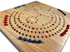 a wooden board game with several different colored beads on it and an arrow in the middle