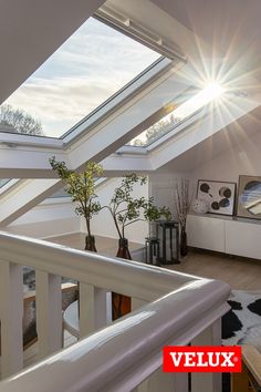 the sun shines brightly through the roof windows in this living room with white walls and wood flooring