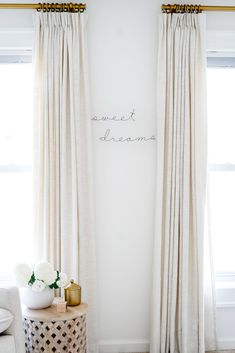 a white room with two curtains and a small table in front of the window that says sweet dreams