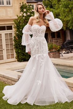 a woman in a white wedding dress standing next to a pool and posing for the camera