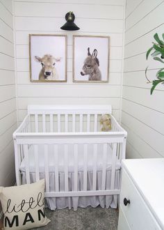 a baby's room with two pictures on the wall and a white crib