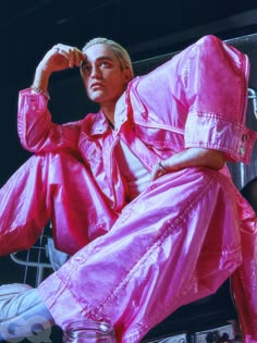 a man sitting on top of a metal rack wearing pink raincoats and holding his hands to his head