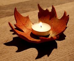 a candle that is sitting on top of a table with leaves in the shape of a leaf