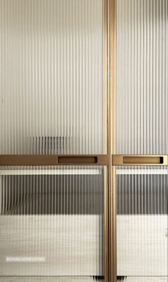 two glass doors with metal handles in front of a white wall that has vertical blinds on it