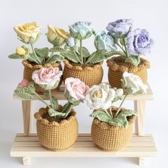 crocheted flowers in baskets sitting on a wooden stand