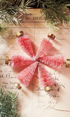 three red christmas trees on top of a piece of paper with writing and bells attached to them