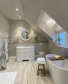 a white bath tub sitting under a bathroom window next to a sink and toilet in a room