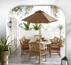 an outdoor dining table and chairs with an umbrella over it on a patio area next to a potted plant