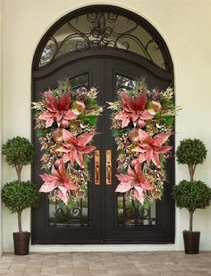 two large wreaths with flowers are on the front door of a home in florida