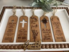 three wooden tags with the names of different people on them, hanging from a tray