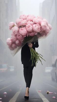 a woman is walking down the street with pink flowers on her head and holding a bouquet