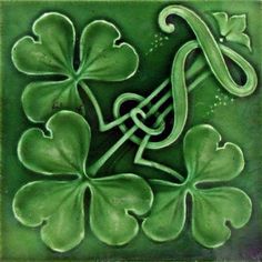 a green tile with four leaf clovers and a snake in the center on it