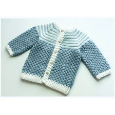 a blue and white knitted sweater with buttons on the front, sitting on top of a table