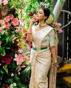 a woman standing in front of flowers wearing a sari