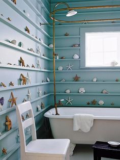 a bath room with a tub and a chair next to a wall covered in shells