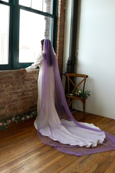 a woman in a wedding dress looking out the window with her veil draped over her head