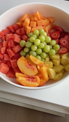 a white bowl filled with fruit on top of a table