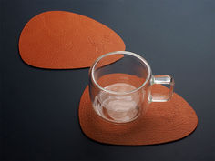 two glass mugs sitting on top of orange placemats next to each other