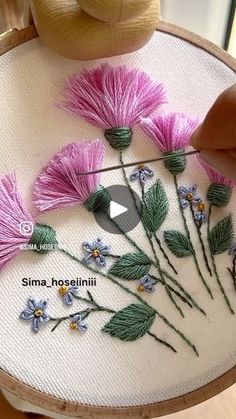 someone is stitching flowers on a piece of fabric