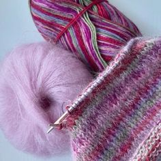 two skeins of yarn and a ball of knitting needles on a white surface