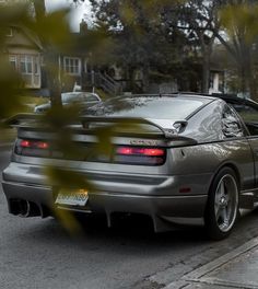 a silver sports car parked on the side of the road in front of a house