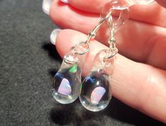 Make a splash with these Mermaid's Tears earrings!  These gorgeous hand-blown teardrop earrings are made with only the highest quality borosilicate glass and features a mesmerizing Gilson opal polished nugget that shimmers with blue, green, yellow, and even a hint of red within the opal encased in glass. These opals flash different colors when angled in different directions and are pictured with sterling silver fishhooks. These blown glass opal earrings come mounted on sturdy sterling silver fis Hypoallergenic Glass Teardrop Jewelry, Clear Teardrop Jewelry With Matching Earrings, Clear Teardrop Earrings For Pierced Ears, Unique Teardrop Hypoallergenic Jewelry, Unique Hypoallergenic Teardrop Dangle Earrings, Clear Drop Earrings Hypoallergenic, Clear Teardrop Glass Earrings, Unique Hypoallergenic Teardrop Jewelry, Unique Hypoallergenic Teardrop Earrings