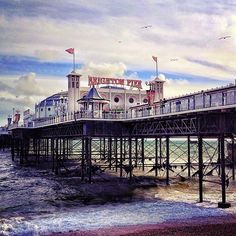 an old pier on the beach with seagulls flying over it