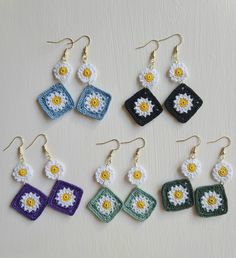 six crocheted earrings with white and yellow flowers on them, all in different colors