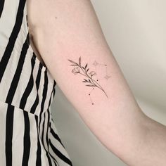 a woman's arm with a small flower tattoo on the left side of her arm