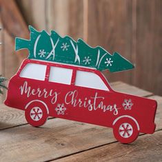 a red van with christmas trees on top is sitting next to a small pine tree