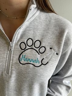 a woman wearing a gray sweatshirt with a dog paw on the front and name hannah on the back