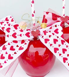 two red apples with hearts on them and candles sticking out of the top are decorated with ribbons