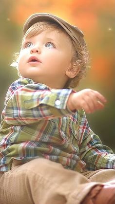 a young boy sitting on the ground with his hands out and looking up at something