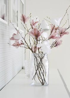 a vase filled with pink flowers sitting on top of a white counter next to a window