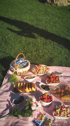 a picnic blanket with food on it in the grass