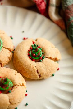 three cookies with green and red sprinkles on a white plate