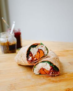 there is a burrito cut in half and sitting on the table next to a jar of ketchup