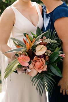 two women standing next to each other holding flowers