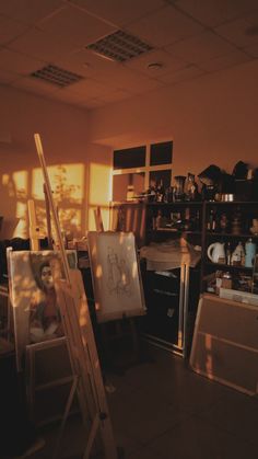 an artist's easel sitting in the middle of a room filled with paintings