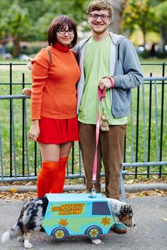 a man and woman standing next to each other with a dog on a leash in front of them