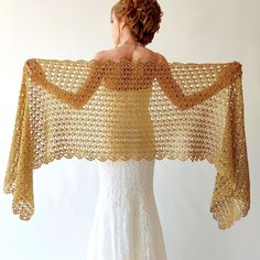 a woman in a white dress is wearing a crocheted shawl with gold trim