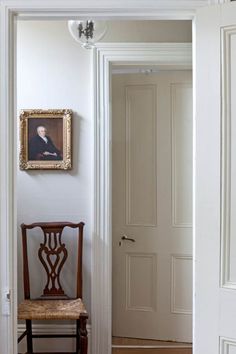 a chair sitting in front of a doorway with a painting on the wall above it