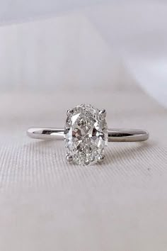 an oval cut diamond ring on a white surface