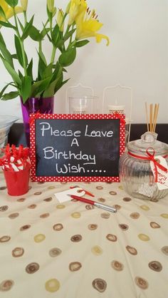 there is a sign that says please leave a birthday wish with flowers in vases